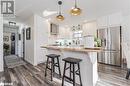Kitchen with backsplash, butcher block countertops, attractive lighting, stainless steel refrigerator with ice dispenser, and wall chimney range hood Kitchen with backsplash, butcher block countertops, attractive lighting, stainless steel refrigerator with ice dispenser, and wall chimney range hood