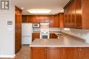 Kitchen with white appliances, a sink, under cabinet range hood, a peninsula, and recessed lighting Kitchen with white appliances, a sink, under cabinet range hood, a peninsula, and recessed lighting