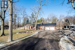 Single story home with asphalt driveway, a chimney, a garage, a front lawn, and brick siding