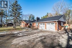 View of front of property with a metal roof, a chimney, brick siding, driveway, and an attached garage