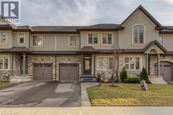 View of front of property with stone siding, stucco siding, a front yard, driveway, and an attached garage