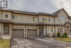 View of front of property with stucco siding, driveway, stone siding, and an attached garage