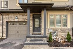 Property entrance with stone siding, an attached garage, driveway, and stucco siding
