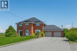 View of front of home with a front yard, asphalt driveway, brick siding, a chimney, and an attached garage