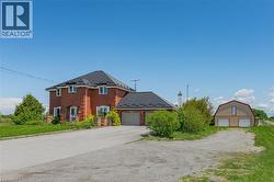 View of front of house featuring brick siding, an outbuilding, driveway, and a detached garage