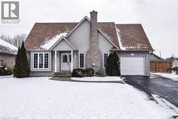 View of front of home featuring a chimney, asphalt driveway, and a garage