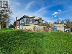 The property features a large grassy yard, a visible deck with railings, and a side entrance with stairs