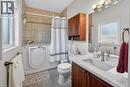 Bathroom featuring a walk-in tub with a shower enclosure, tile surround, single vanity and linen closet.
