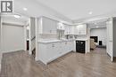 Compact kitchenette featuring white shaker cabinetry, light-toned countertops, and laminate flooring.