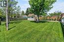 Expansive green lawn with a mature shade tree, offering a storage shed, a interlock patio area, and perimeter fencing.