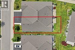 Aerial view showcasing a property with a gray shingle roof, a paved driveway, and a concrete pathway