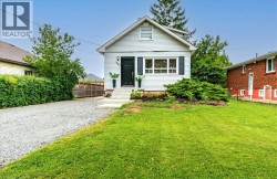 Gable roofline, light-colored horizontal siding, dark front door, white window trim, and a gravel driveway