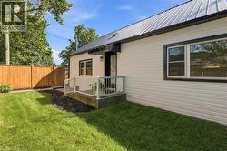 White horizontal siding with black trim windows, a metal roof, and a wooden privacy fence
