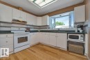 Kitchen featuring a bay window, white cabinetry, dark countertops, tile backsplash, and wood-finish flooring