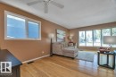 Spacious living area featuring wood-finish flooring, a ceiling fan, and multiple windows
