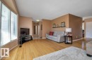 Bright living space featuring wood-finish flooring, a large bay window with horizontal blinds, and a neutral wall color palette