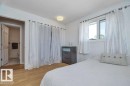 Bedroom featuring wood-finish flooring, a window with window treatments, and a ceiling-mounted light fixture