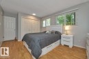 Bedroom featuring wood-finish flooring, two large windows with blinds, and white bi-fold closet doors