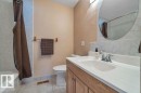 Bathroom featuring a wood-finish vanity with an integrated sink, polished chrome faucet, and a large circular mirror