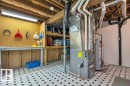 Utility room featuring a workbench with pegboard organization, built-in shelving, exposed ceiling joists, and patterned floor tile