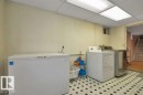 Utility area featuring patterned tile flooring, a drop ceiling with recessed lighting, and a small window
