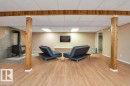 Spacious lower level featuring wood-finish flooring, exposed wood columns and beam, a wood-burning stove with tile surround, and recessed ceiling lighting