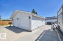 Detached garage featuring two overhead doors, horizontal vinyl siding, and two black wall-mounted exterior light fixtures