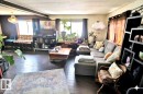 Living area featuring dark wood floors, large windows with dark curtains, and a decorative chandelier