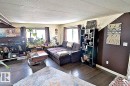 The living area features dark wood-style flooring, a large window with dark curtains, and a textured white ceiling