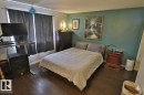 This room features dark hardwood flooring, a green accent wall, and a window with dark curtains
