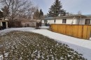 The property features a spacious rear yard with a lawn, a wooden deck with a privacy fence, and a storage shed