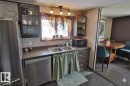 The kitchen features a double stainless steel sink, a stainless steel dishwasher, and a refrigerator