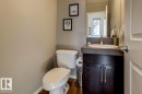 Compact powder room featuring a white toilet, wood-finish flooring, and a dark wood vanity with an integrated sink and countertop