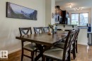 Open-concept dining area featuring wood-finish flooring, a kitchen pass-through with a countertop, dark wood cabinetry, and a large window