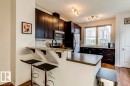 Kitchen featuring dark wood-finish cabinetry, stainless steel appliances, and a breakfast bar with stone-finish countertops