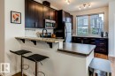 Modern kitchen featuring dark wood-finish cabinetry, stainless steel appliances, a granite breakfast bar, and wood-finish flooring