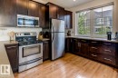 Kitchen featuring dark wood cabinetry, stainless steel appliances, light countertops, and wood-finish flooring