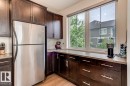 Kitchen featuring dark wood cabinetry, stainless steel refrigerator, light countertops, and a large window