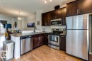 Kitchen featuring dark wood cabinetry, stainless steel appliances, light-toned countertops, wood-finish flooring, and a breakfast bar