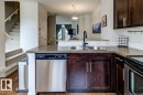 Kitchen featuring dark wood cabinetry, a stainless steel double basin sink with a matte black faucet, and a stainless steel dishwasher