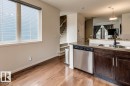 Kitchen featuring dark wood cabinetry, stainless steel dishwasher, an undermount sink with a matte black faucet, and a light-colored countertop