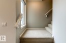 Carpeted staircase featuring a window and painted handrail