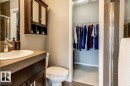 Bathroom featuring a dark wood-finish vanity with an undermount sink, a coordinating wall-mounted mirrored medicine cabinet, a standard toilet, and a glass-enclosed shower