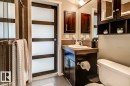 Contemporary bathroom featuring a dark wood vanity with an integrated sink, a large wall mirror, and a sleek glass-enclosed shower