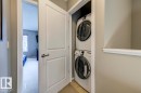 Dedicated laundry closet featuring a stacked washer and dryer unit, neutral wall paint, and white trim