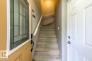 Entryway featuring a decorative glass panel door with a dark bronze handle, a carpeted staircase with a white handrail, and a paneled interior door with chrome hardware