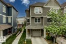 Three-story townhome featuring muted green siding, white trim, and a two-car garage