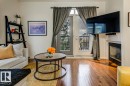 Living area featuring wood-finish flooring, a built-in fireplace, and a glass-paned door leading to an outdoor balcony with a metal railing