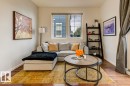 Living area featuring wood-finish flooring, white baseboards, and a window with a roller shade
