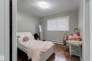 Bedroom featuring wood-finish flooring, light grey painted walls, a flush-mount ceiling light fixture, and a window with blinds
